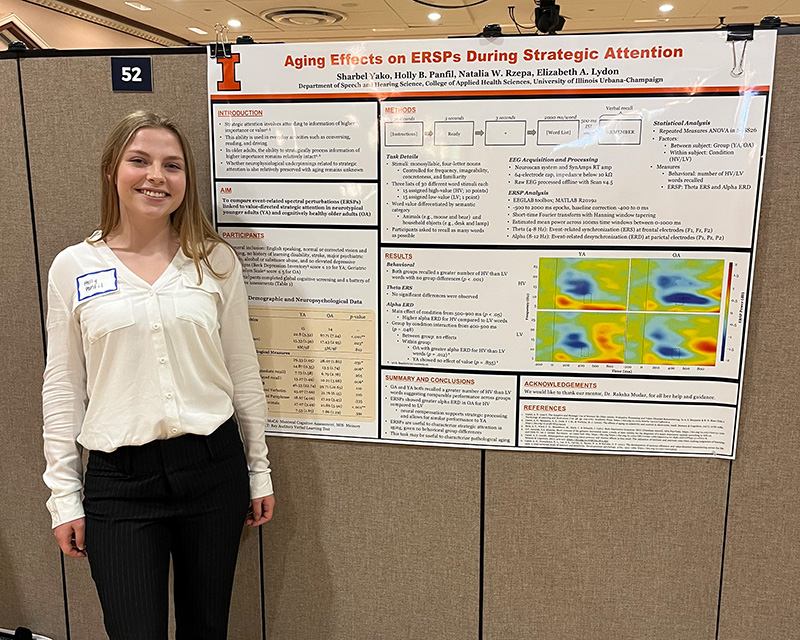 Holly standing, smiling next to a research poster